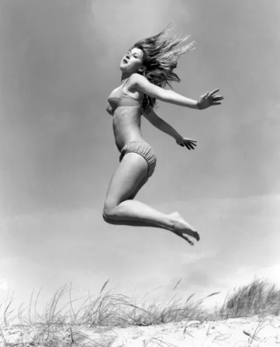Framed Print : Young woman leaps up from a sand dune, Cornwall Framed Print : Young woman leaps up from a sand dune, Cornwall