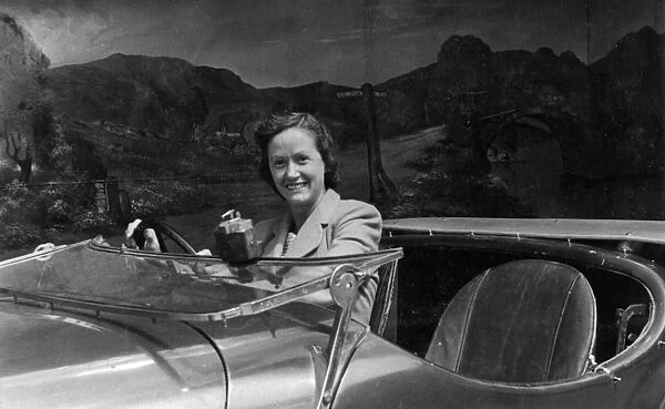 Young woman at wheel of car in studio photo