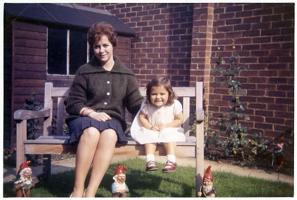 Young woman and her young niece on arden bench with gnomes