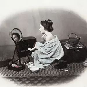 1860s Japan - portrait of a young woman putting on make-up at a mirror Felice or Felix