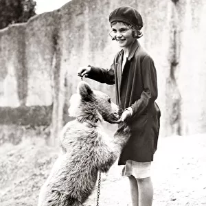1930s press print - girl at zoo with bear on chain