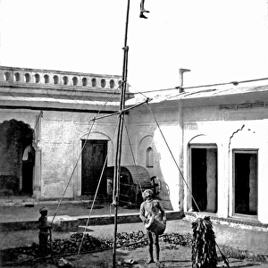 Acrobat on a pole, with drummer below, India