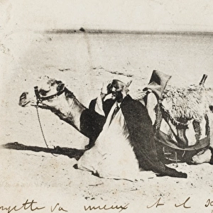 An Algerian Man prays alongside his camel