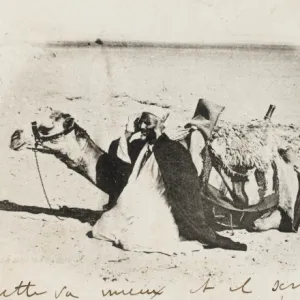 An Algerian Man prays alongside his camel