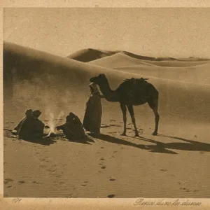 Arabs and camel resting in the sand dunes, Algeria