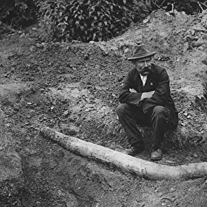 An archaeologist sits next to the unearthed remains of a st