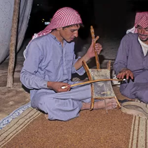 Bedouin men in tent in Syrian desert, one plays a rababah