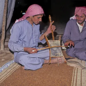 Bedouin men in tent in Syrian desert, one plays a rababah