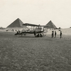 A biplane in the Egyptian desert, with the pyramids