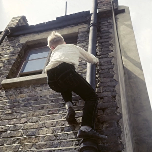 Boy climbing drainpipe on a Balham house, SW London