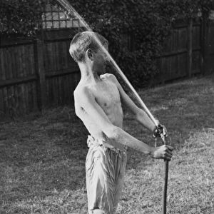 Boy plays with water hose 1933