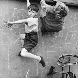 Two boys climbing wall on a Balham street, SW London