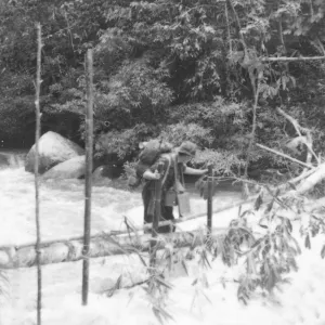 British soldier crossing the river on a log, Malaya, 1946