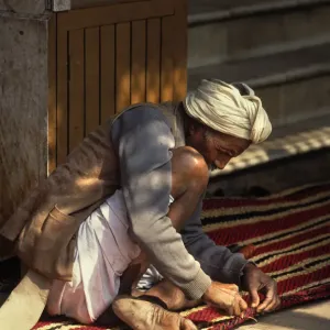Carpet maker stitches the hem of a striped carpet, Rajasthan Carpet maker stitches the hem of a striped carpet, Rajasthan