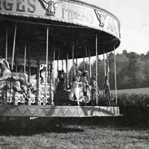 Children on a merry-go-round at Hascombe fair, Surrey, England. Date: early 1930s