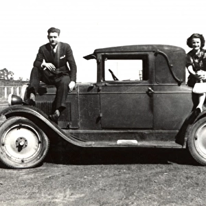 Couple pose for a picture on a small car