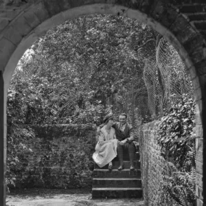 Couple sitting on steps in a garden, Frensham, Surrey