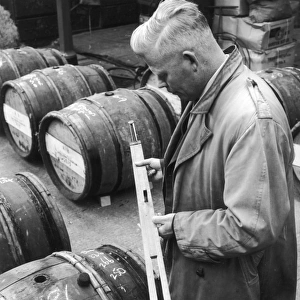 Customs Official checks the volume of wine in a barrel