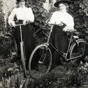 Two Edwardian women with their bicycles in a garden