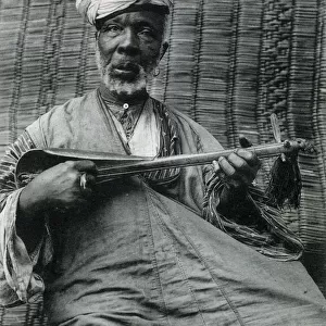 Elderly Moroccan man playing a sintir, also known as the guembri, gimbri or hejhouj, is a three-stringed skin-covered bass plucked lute used by the Gnawa people