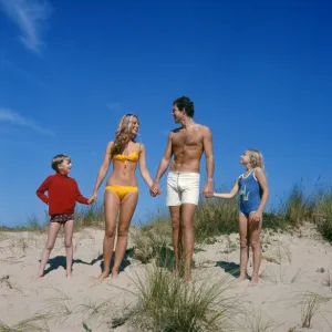 Family holding hands on sand dunes