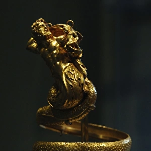 Gold armband with male triton holding a small winged Eros. (