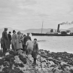 Group of people on shore with steamboat on the sea