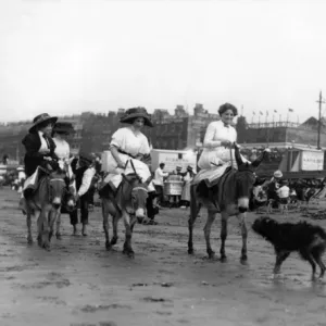 Holidaymakers riding donkeys on a beach