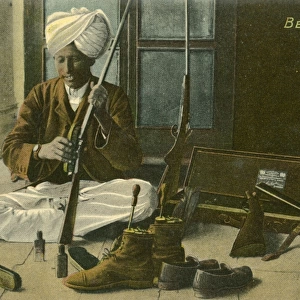 Indian Bearer - cleaning his Masters shoes and rifle