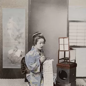 Japanese geisha in an ornate kimono writing a letter