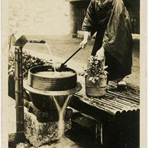 A Japanese man watering his flowers from a water pump
