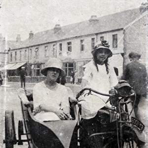 Two ladies on veteran motorcycle combination in street