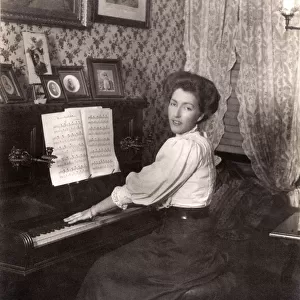 Lady playing an upright piano in her front room