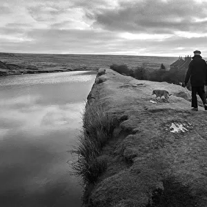 A man walks his dog along an embankment in Blaenavon, Wales