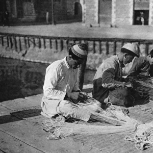 Three men repairing fishing nets, Holy Land