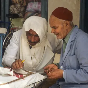 Two men sit beside stall in the market at Houmt Souk, Djerba Two men sit beside stall in the market at Houmt Souk, Djerba