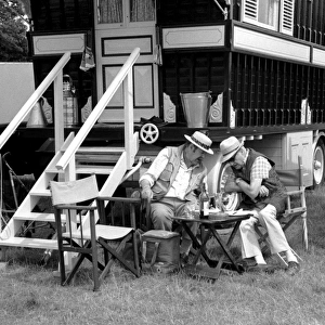 Two men sitting outside a caravan