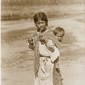 A Mexican girl carrying her younger brother