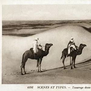 Nomadic Tuaregs riding camels amongst the Saharan Dunes - North Africa
