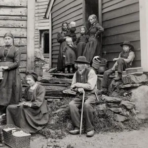 Norway, rural family outside home with spinning wheel