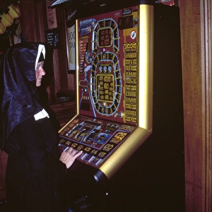 Nun playing on a fruit machine