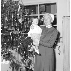 Nurse holding child next to Christmas tree