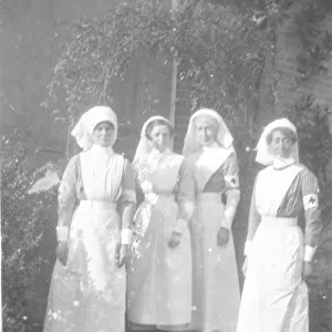 Four nurses in uniform, with red cross armbands