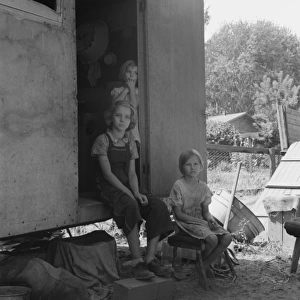 The oldest girl seated in the doorway of the house trailer c