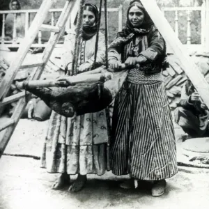 Two Persian women rocking a goatskin to churn milk