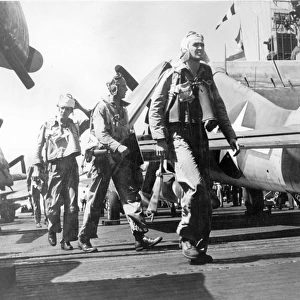 Pilots walk past a Grumman F6F Hellcat on a carrier deck