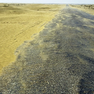 Sand dunes in a wind - Karakum desert encroach on a road