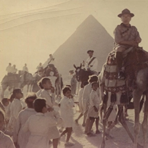 Scout leader on camel in front of pyramid, Egypt