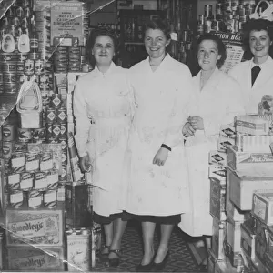 Four shop workers line up for a photograph in a well-stocked grocery store