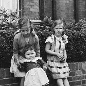 Three sisters sitting on a front garden wall